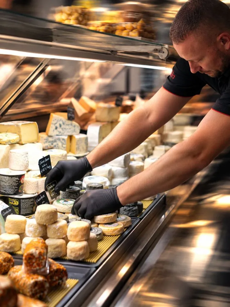 Le fromager installe les fromages dans sa vitrine