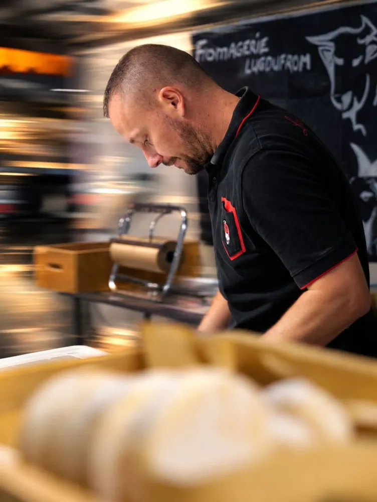 Le fromager de Lugdufrom derrière son stand au marché